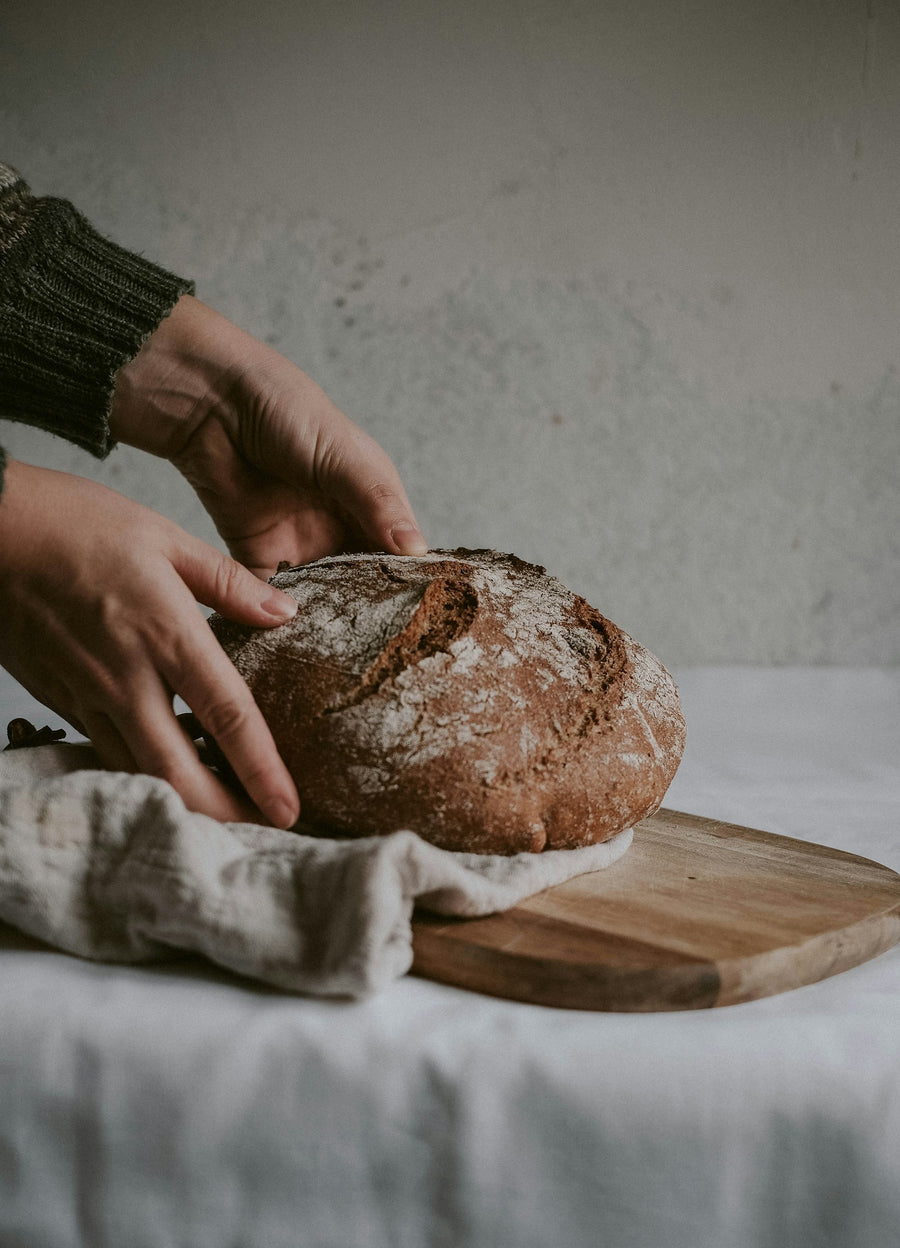 Person hält ein aufgeschnittenes Sauerteigbrot als Symbolbild für den Unterschied zwischen Sauerteig und Hefe
