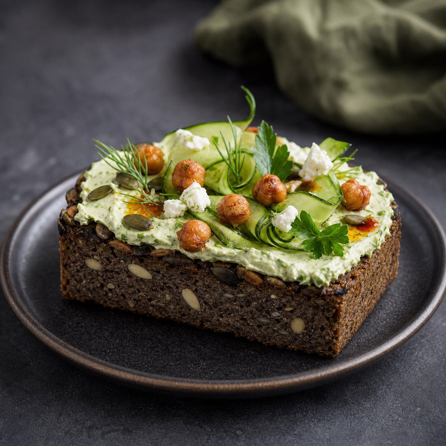 Saftkorn Kürbis-Mandel Green-Goddess Toast mit Kräuter-Feta-Creme, Gurke und knusprigen Kichererbsen
