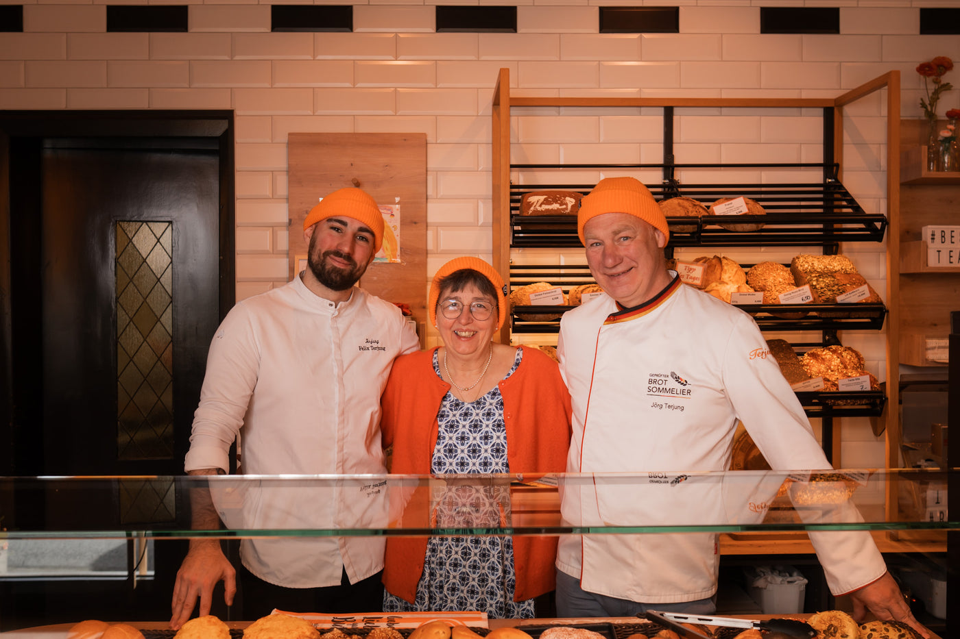 Das Team der Bäckerei Terjung mit orangefarbenen Mützen an der Brottheke